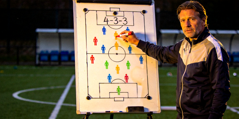 足球教练在战术板上绘制4-3-3阵型示意图讲解战术